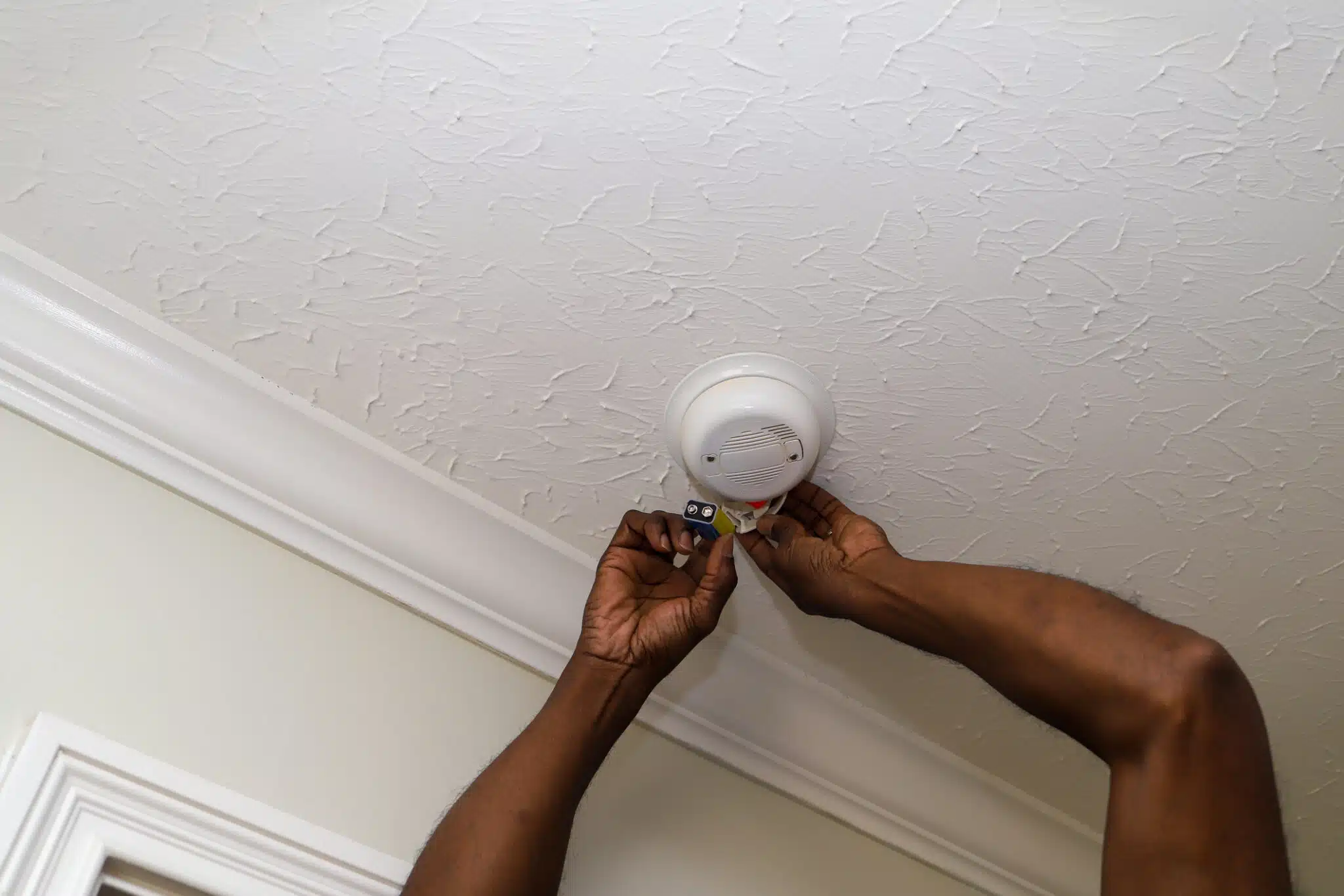 Man changing a battery in a smoke detectors.